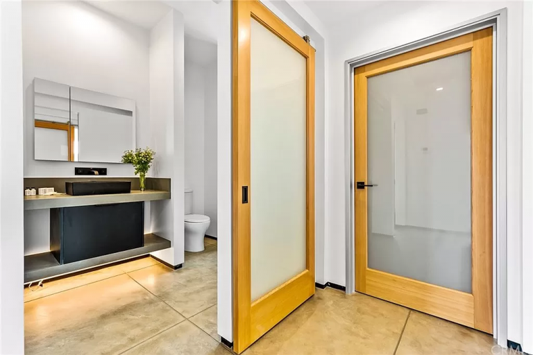 A bathroom with two doors and a toilet.