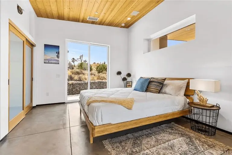 A bedroom with a bed, nightstand and window.