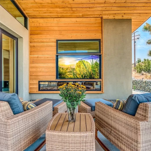 A television is mounted on the wall of a patio.