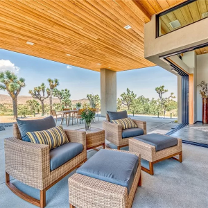 A patio with chairs and ottomans on the ground.