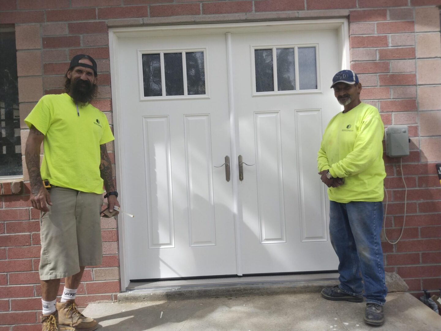 Two men standing in front of a garage door.